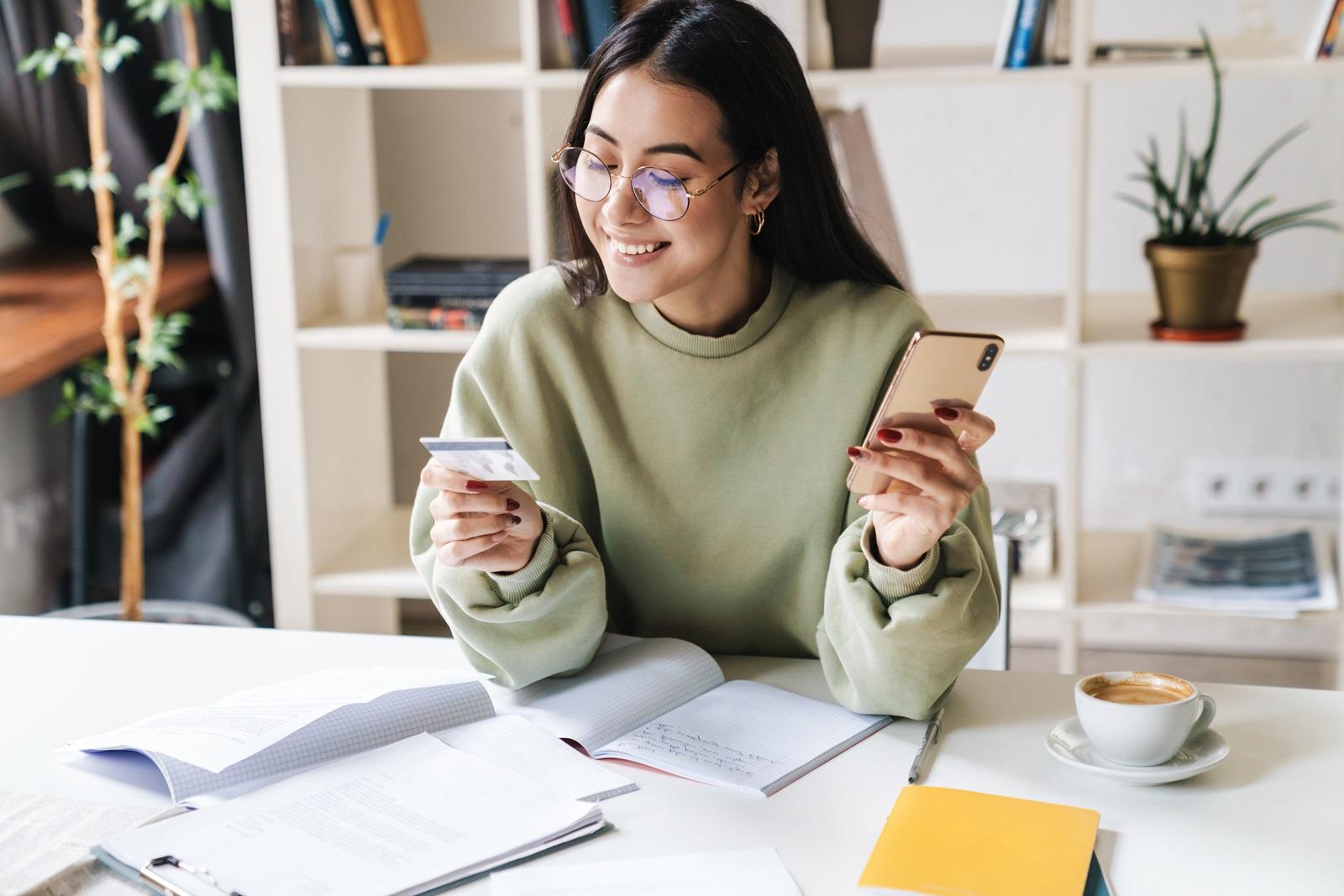 A young college student checks her credit card balance on her smartphone.